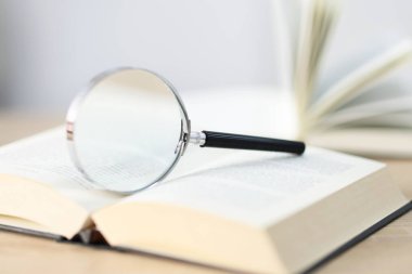 Büyüteç ve kitaplar masanın üzerinde, yakın plan.