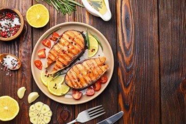 Lezzetli ızgara somon bifteği, limon, biberiye ve domatesle servis edilir. Metin için boşluk