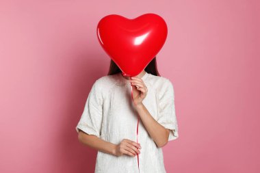 Sevgililer Günü. Pembe arka planda kalp şeklinde balonu olan kadın.