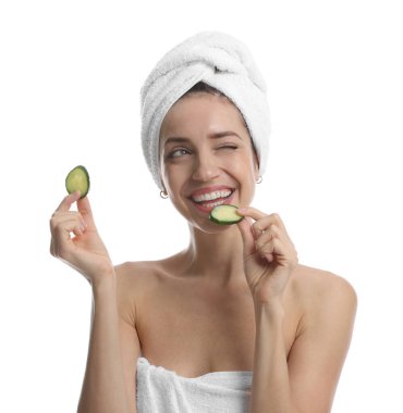 Havluya sarılı güzel bir kadın ve beyaz arka planda salatalık dilimleri.