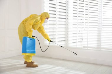 Koruyucu giysiler içinde böcek ilacı sıkan haşere kontrol görevlisi.
