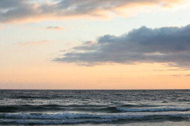 Gün batımında denizin üzerinde bulutlarla güzel bir gökyüzü manzarası.