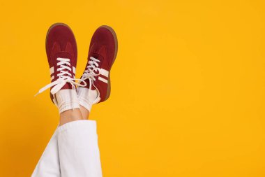 Sarı arka planda şık bordo ayakkabılar giyen bir kadın, yakın plan. Metin için boşluk