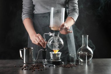 Gri masada vakumlu kahve makinesiyle kahve yapan kadın, yakın plan.