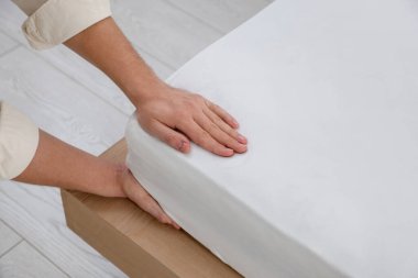 Adam yatak çarşaflarını kapalı bir yere koyuyor.