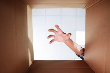 Karton kutuya uzanan adam, yakın plan. İçeriden görüntüle