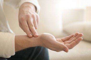 Adam içeride parmaklarıyla nabzını kontrol ediyor, yakın plan. Metin için boşluk