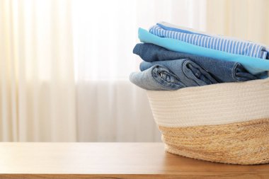 Ahşap masanın üzerinde giysileri olan çamaşır sepeti, yakın plan. Metin için boşluk