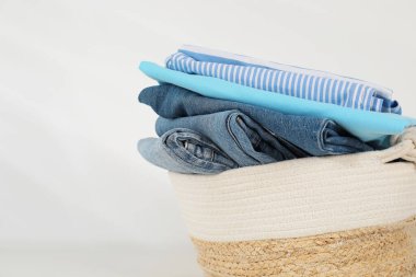 Çamaşır sepetinin içinde beyaz duvarın yanındaki masada giysiler var, yakın plan. Metin için boşluk