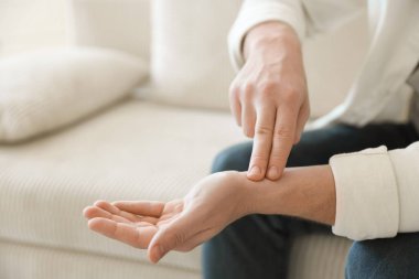 Adam içeride parmaklarıyla nabzını kontrol ediyor, yakın plan. Metin için boşluk