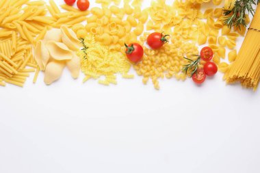 Farklı türde çiğ makarna, domates, biberiye ve kekik, beyaz masa, düz yatak. Metin için boşluk