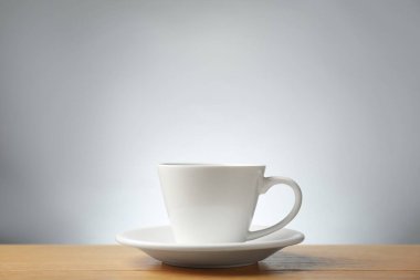 Aromatik kahve fincanda, tahta masada, gri arka planda.