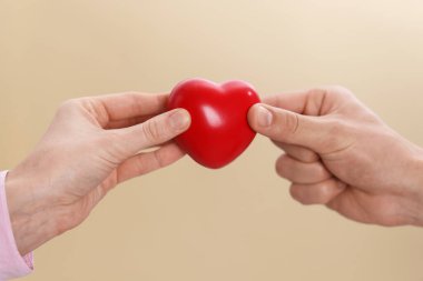 Bej arka planda kırmızı kalpli insanlar, yakın plan.