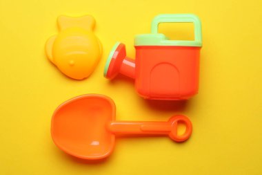 Sarı arka planda çocukların plaj oyuncakları, düz yatış