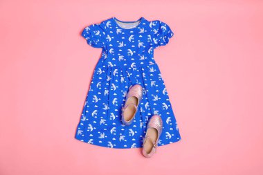 Pembe arka planda şık çocuk kıyafetleri ve ayakkabıları var.