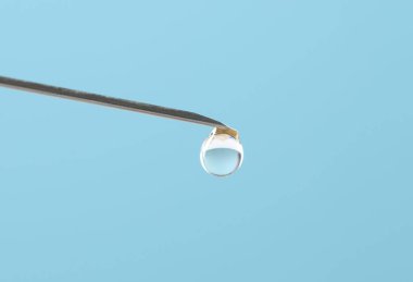 Tüp bebek tedavisinde. Açık mavi arka planda sıvı numuneli iğne, yakın plan. Metin için boşluk