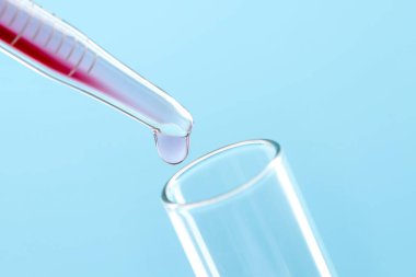 Tüp bebek tedavisinde. Sıvı numuneli boru ve açık mavi arka planda test tüpü, yakın plan