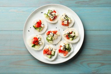 Sebzeli lezzetli pirinç kağıdı cipsi, beyaz peynir ve açık mavi ahşap masada siyah susam tohumu.