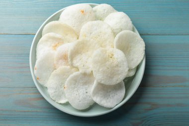 Açık mavi ahşap masa üzerinde leziz pirinç kağıdı parçaları, üst manzara.