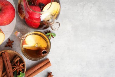 Cam fincanda aromatik meyve çayı, çaydanlık, elma, nane ve baharatlar gri masada, düz yerde. Metin için boşluk