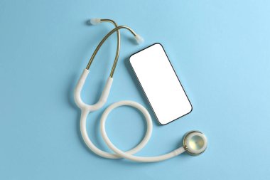 Sağlığınıza. Açık mavi arka planda akıllı telefon ve steteskop, düz konum