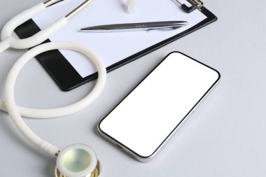 Sağlığınıza. Akıllı telefon, steteskop, arkaplanda pano ve kalem, yakın plan.