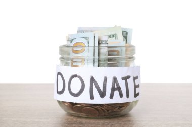 Bağış kavanozu para ile ahşap masa beyaz arka plan