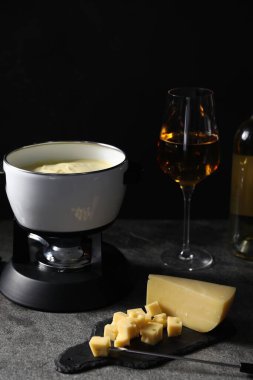 Erimiş peynir, şarap ve atıştırmalıklarla siyah masada fondü tenceresi (caquelon)