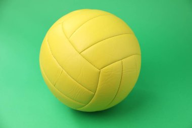 Yeşil zemin üzerinde sarı bir voleybol topu