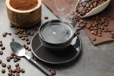 Kahve fincanda, fasulye de gri masada, yakın plan.