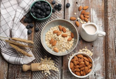 Yulaf gevreği, fındık, badem sütü ve yaban mersini ahşap masada, düz uzanmış