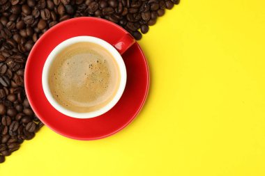 Sarı zemin üzerinde aromatik kahve ve fasulye olan bir fincan. Metin için boşluk