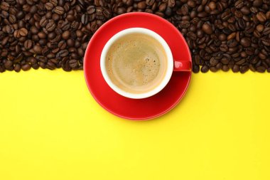Sarı zemin üzerinde aromatik kahve ve fasulye olan bir fincan. Metin için boşluk