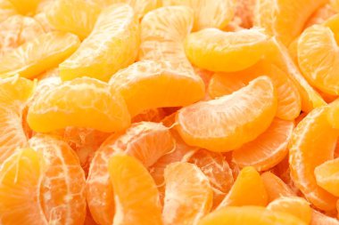 Arka plan olarak birçok olgun soyulmuş mandalina, yakın plan