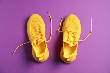 Mor arka planda bir çift şık spor ayakkabı, üst görünüm.
