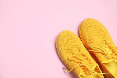 Pembe arka planda şık bir çift spor ayakkabı, üst manzara. Metin için boşluk