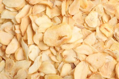 Dried garlic flakes as background, top view