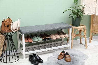 Farklı ayakkabı, aksesuar ve yeşil duvarın yanındaki ev bitkilerinden oluşan ayakkabı deposu.