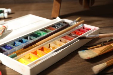 Resimli palet, ahşap masa üzerinde tüpler ve fırçalar, yakın plan.