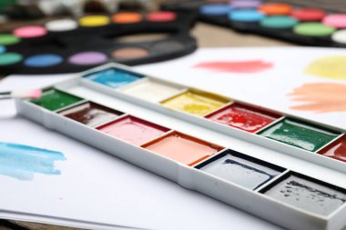 Suluboya resimli paletler, masa üzerinde fırça ve boya, yakın plan