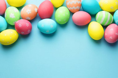 Açık mavi arka planda birçok Paskalya yumurtası boyanmış. Metin için boşluk