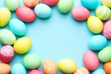 Açık mavi arka planda birçok boyanmış Paskalya yumurtasından yapılmış bir çerçeve. Metin için boşluk