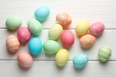 Güzel dekore edilmiş Paskalya yumurtaları beyaz ahşap masa üzerinde, düz yatıyordu.