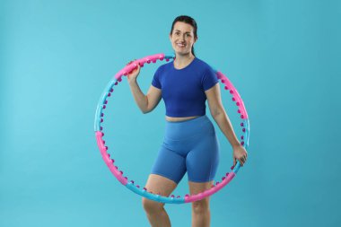 Açık mavi arka planda hula çemberi olan mutlu kadın.