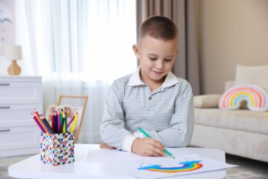 Masada kalemle çizen sevimli küçük çocuk.