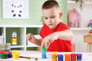 Masasında resim olan sevimli küçük bir çocuk.