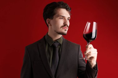 Kırmızı arka planda şarap kadehi olan profesyonel şarap garsonu.