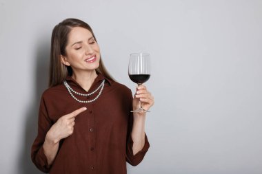 Açık gri arka planda kırmızı şarap kadehi olan profesyonel şarap garsonu. Metin için boşluk