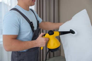 Haşere kontrol görevlisi yastığı temizliyor, kapalı alanda temizliyor, yakın plan.