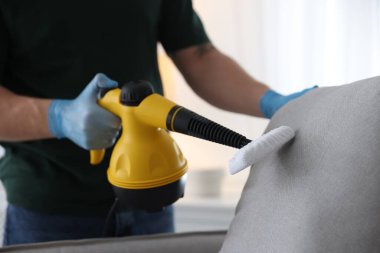 Haşere kontrol işçisi temizlik yastığını içeride buhar temizleyicisiyle temizliyor, yakın plan.